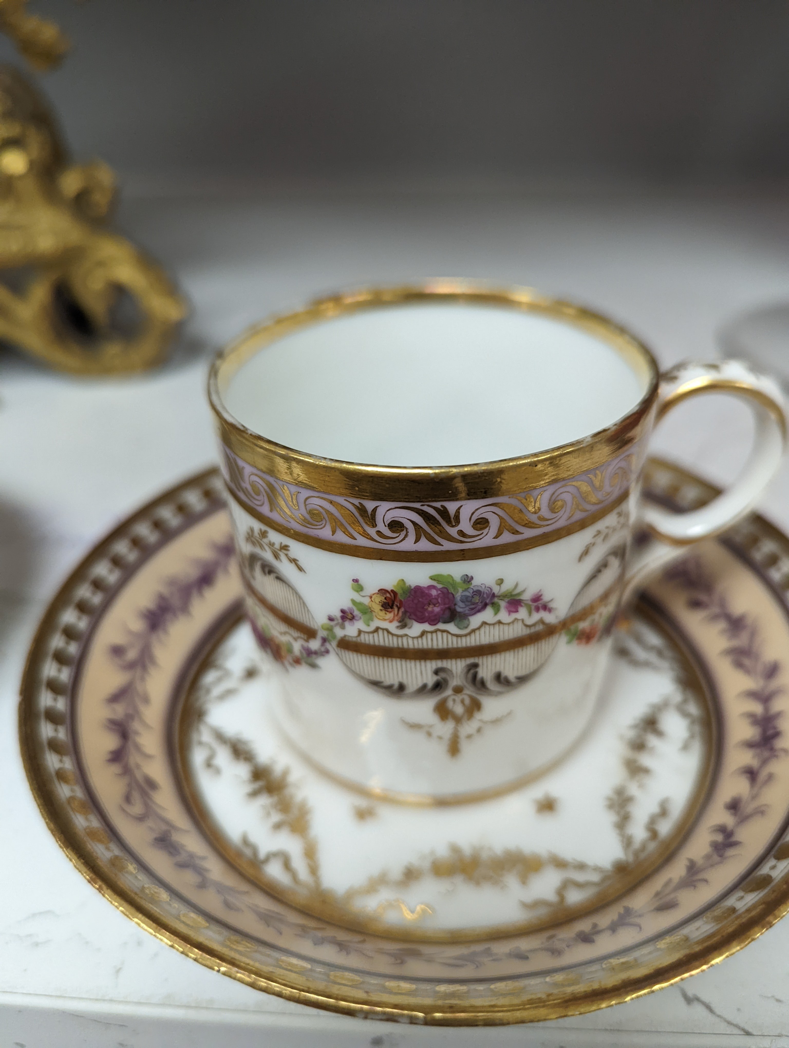 A Duc d'Angouleme coffee can and saucer painted with a puce chain of leaves on a salmon coloured ground and another painted with a flower chain, black feather and a gilt line, latter with stencilled red mark 'Manuf de M